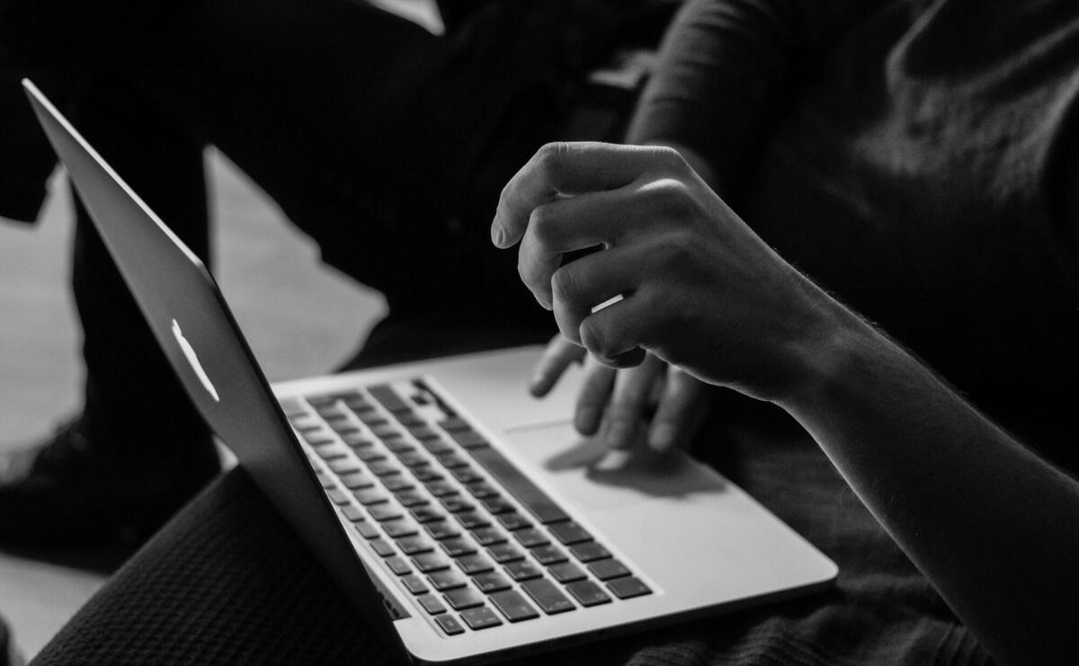 grayscale photo of person using MacBook