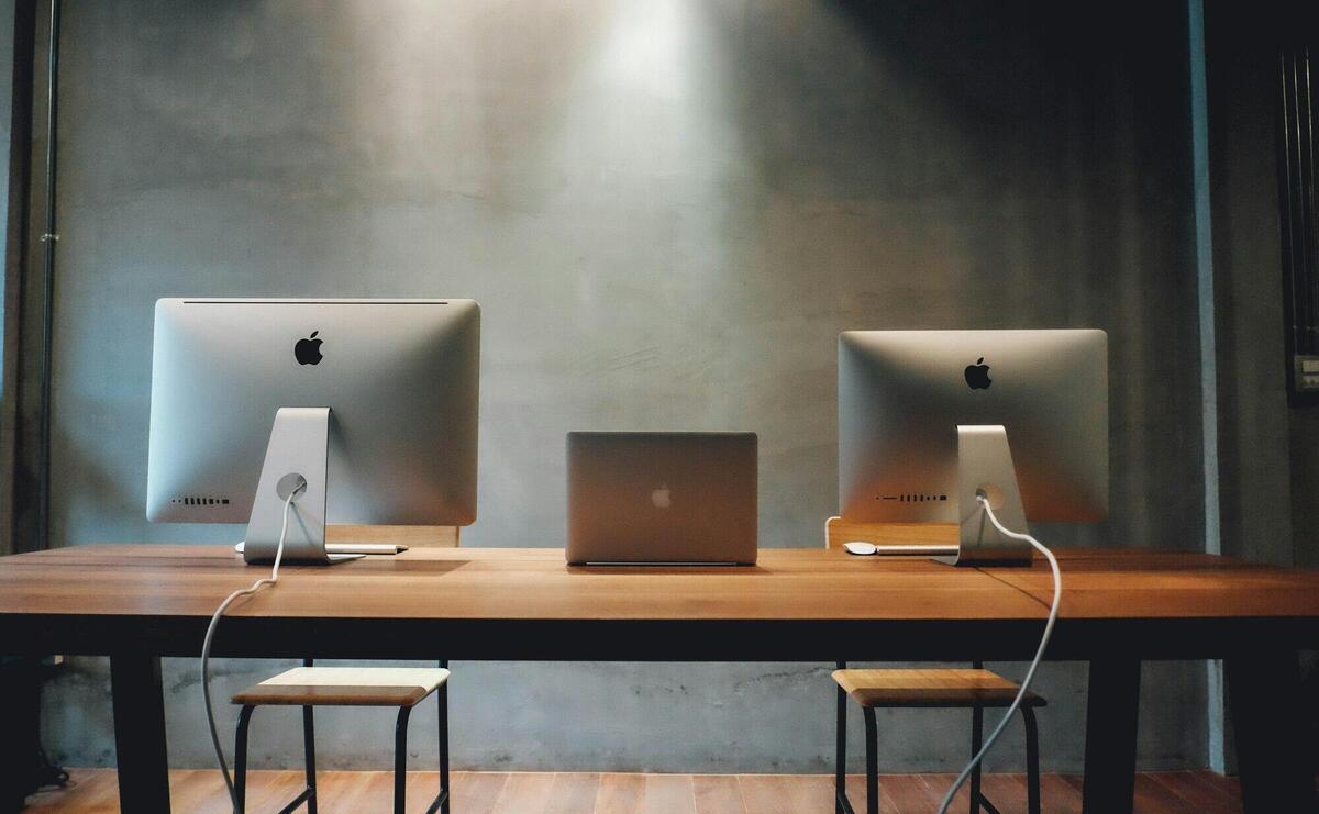 Minimalist office space with dual monitors on a wooden table, promoting a contemporary work environment.