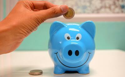 Person Putting Coin in a Piggy Bank