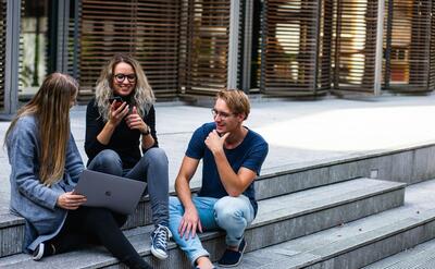 Three Persons Sitting on the Stairs Talking With Each Other