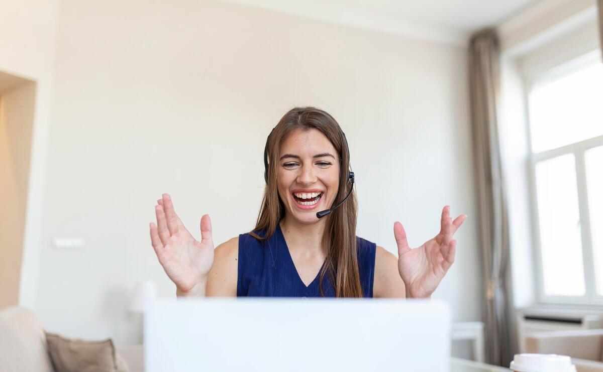 Young woman in headphones speaking looking at laptop.