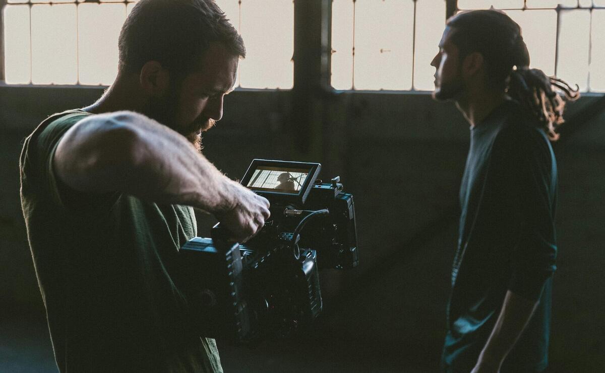 man holding camcorder with man near wall