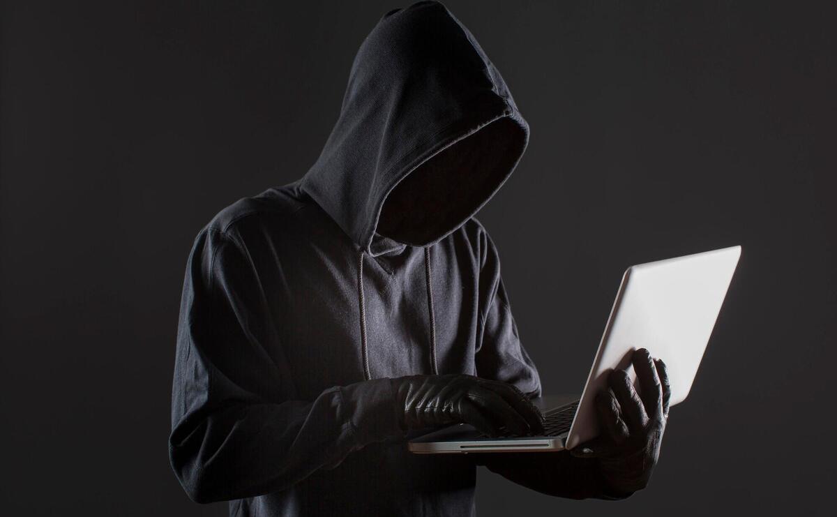 Side view of male hacker with gloves and laptop