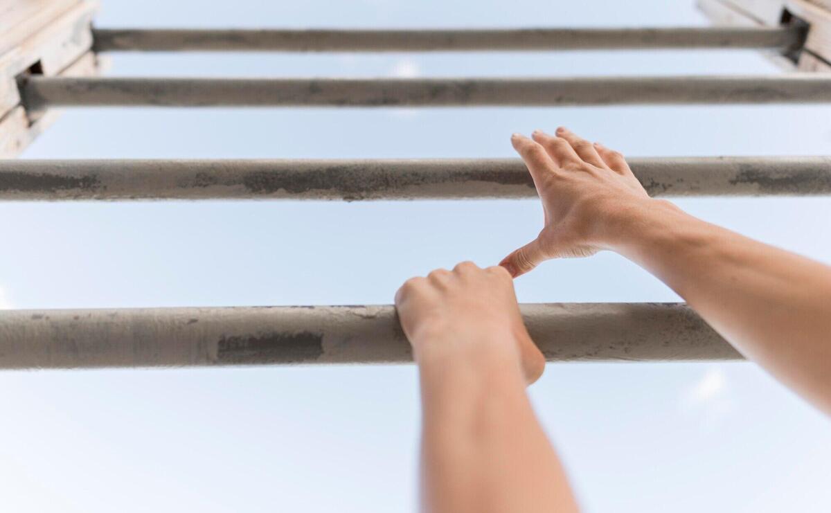 Low angle woman climbing on metal bars