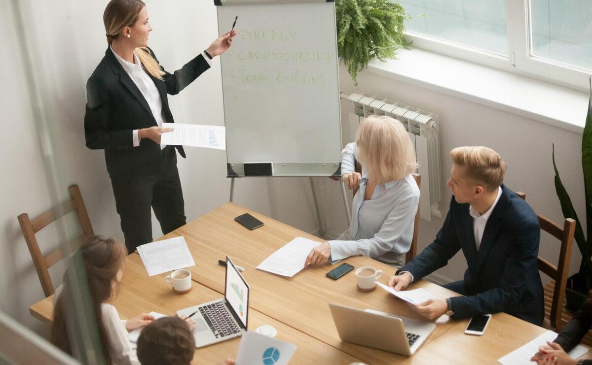 Businesswoman leader giving presentation explaining team goals at group meeting