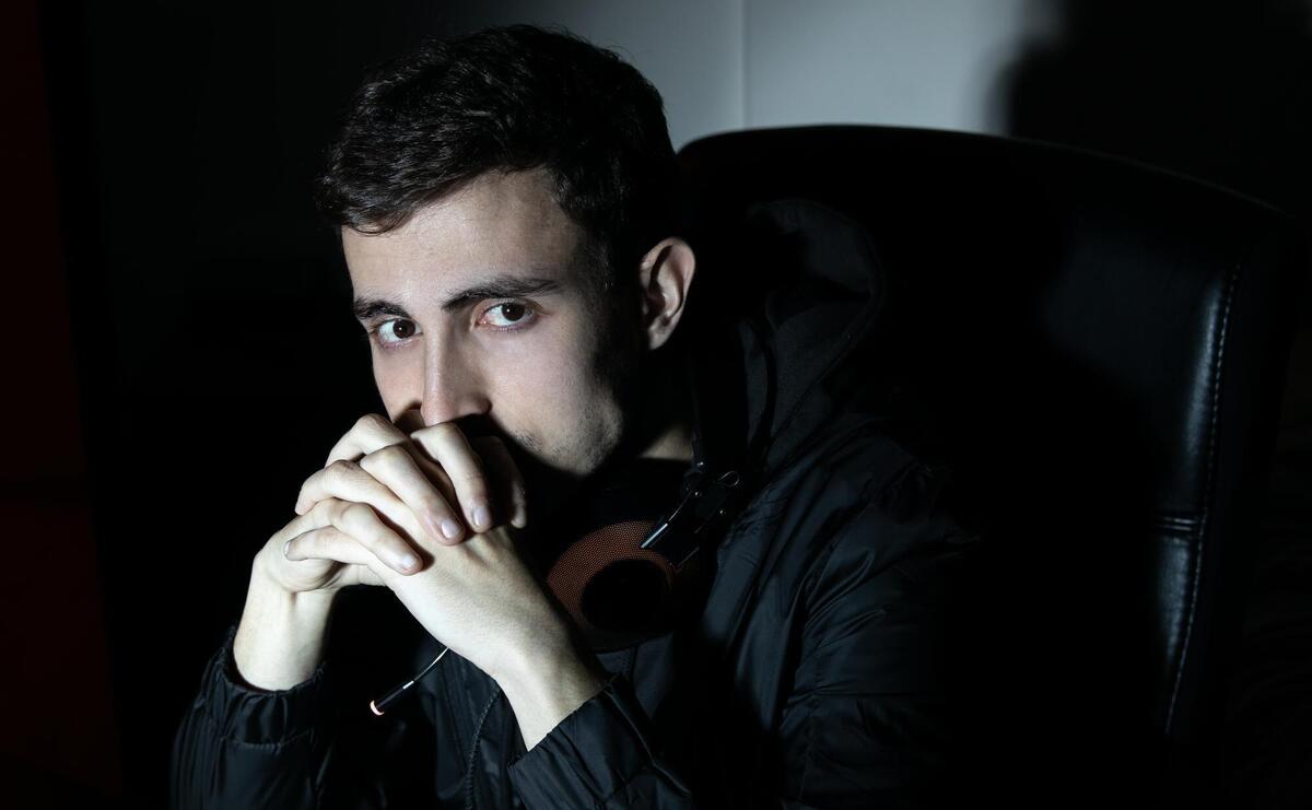 Portrait of young attractive man with earphones. Dark-haired man in casual clothes looking at camera, holding hands near face. Portrait concept