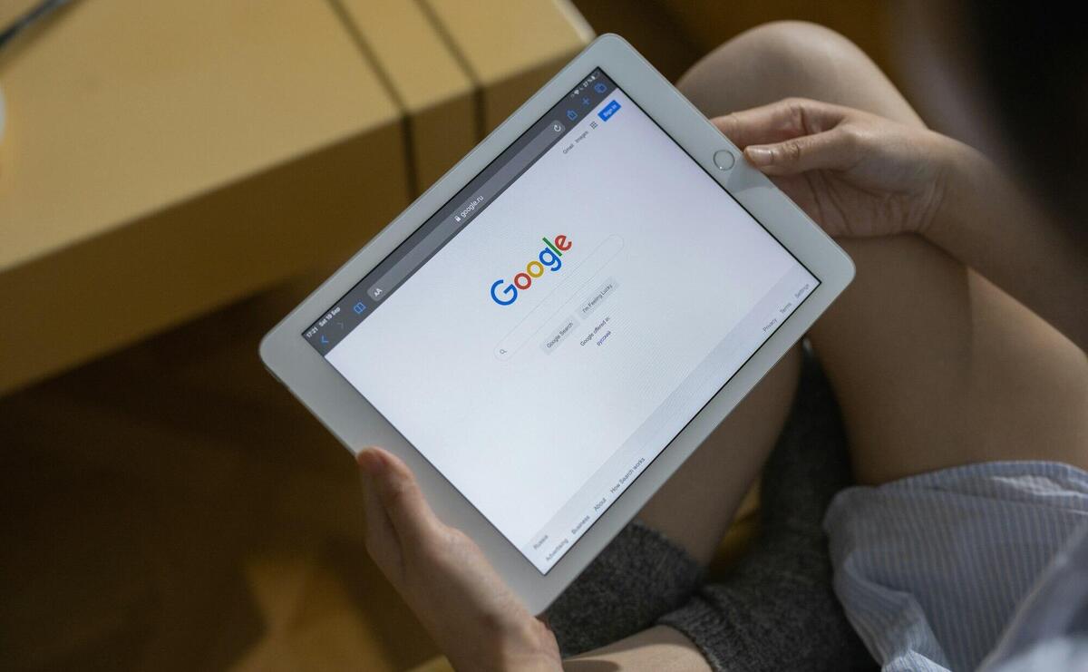 Close-up of hands holding a tablet showing the Google search page.