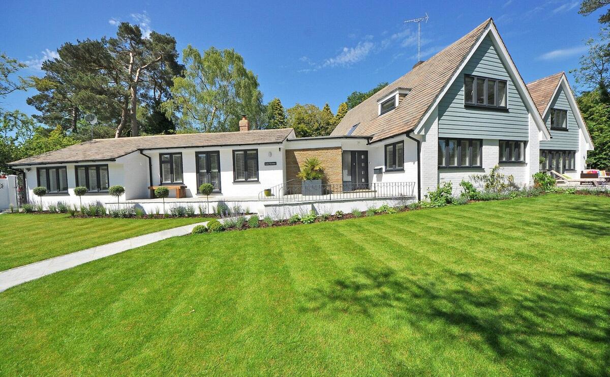 Contemporary house exterior with large manicured lawn and beautiful garden.